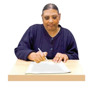 A woman sat at a desk with some paper in front of her. She is writing on the paper.
