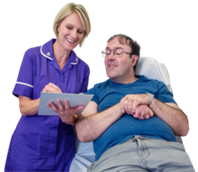 A nurse standing next to a patient who is sat down. The nurse is holding a document and is asking her patient questions. They are both smiling.
